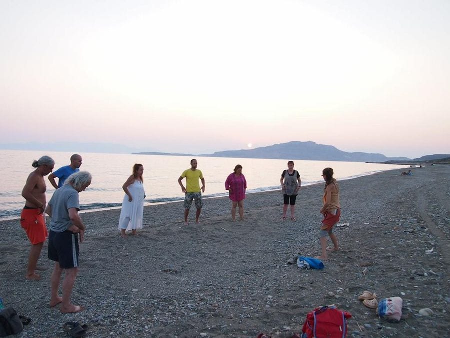people learning and listening to a woman giving lesson of Tai Chi on beach in sunset at Korogonas Ark area